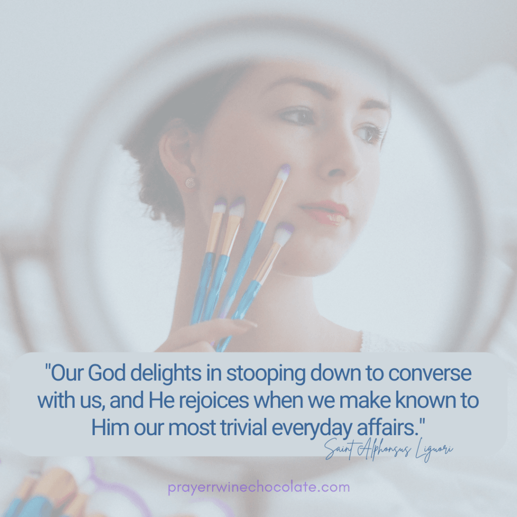 Girl holding make-up brushes against her face, you see her reflection in a round makeup mirror.  The Saint quote on it states "Our God delights in stooping down to converse with us and He rejoices when we make known to Him our most trivial everyday affairs: