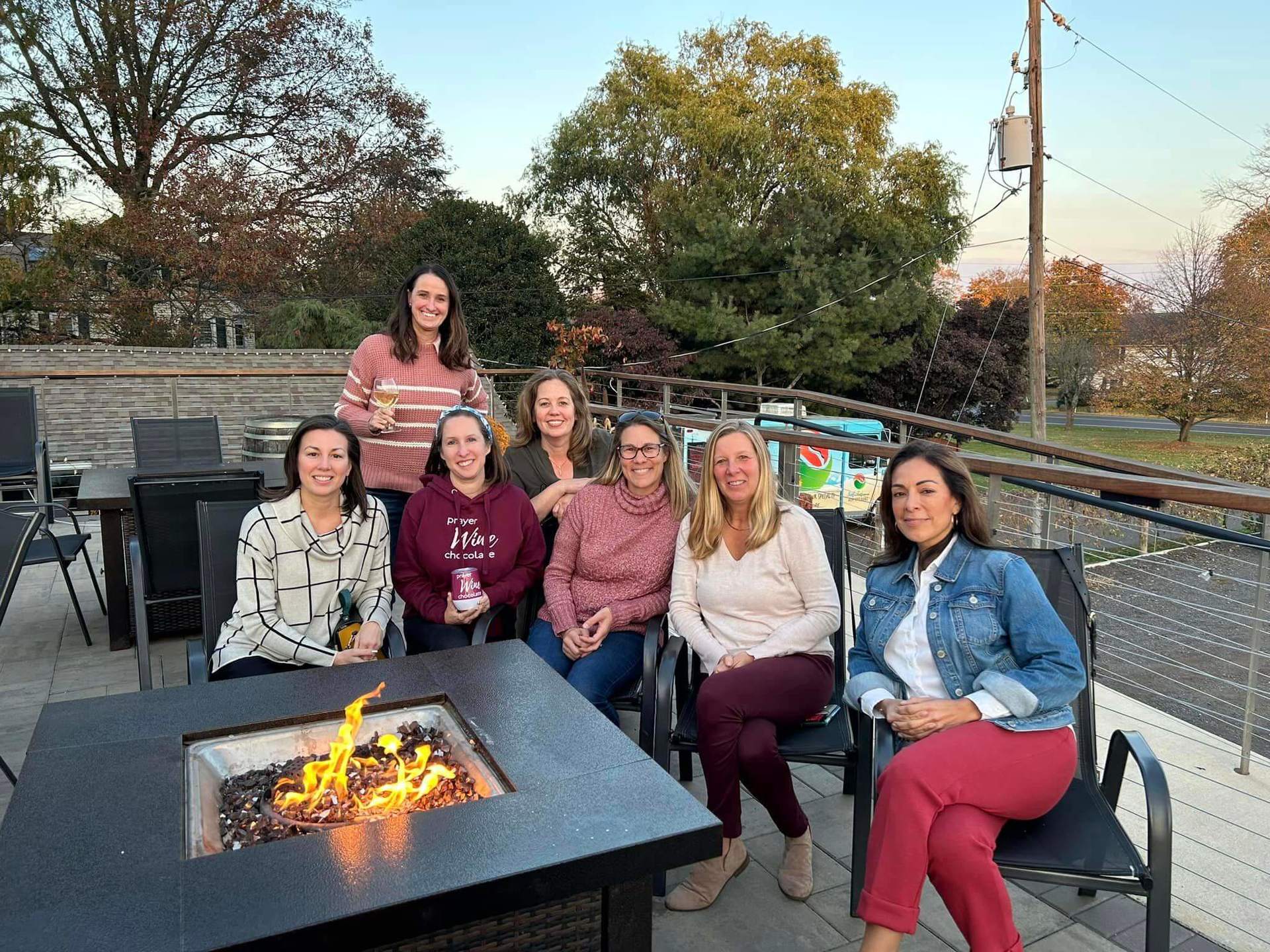 7 women sitting around a fire pit; these women attended the 2023 Prayer Wine Chocolate Retreat